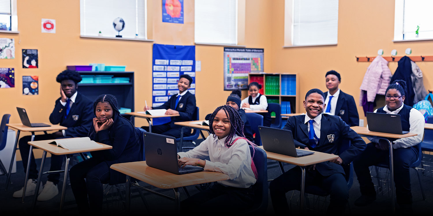 Smiling students at desks in a classroom.